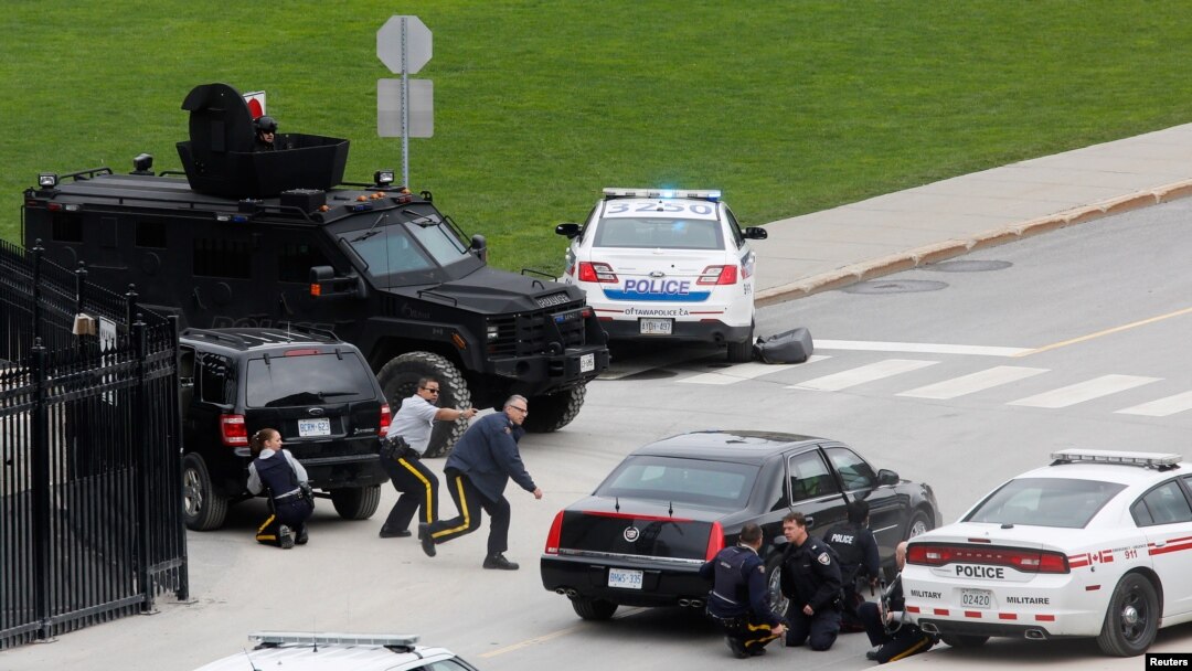 Police officers take cover near Parliament Hill following a shooting incident in Ottawa, October 22, 2014.