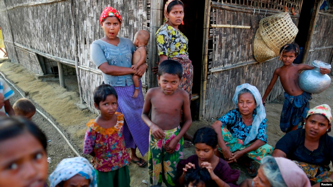 FILE - Rohingya Muslims pass time near their shelter at a refugee camp outside Sittwe, Myanmar.