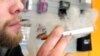FILE - A sales associate demonstrates the use of an electronic cigarette and the smokelike vapor that comes from it in Aurora, Colo., March 2, 2011.