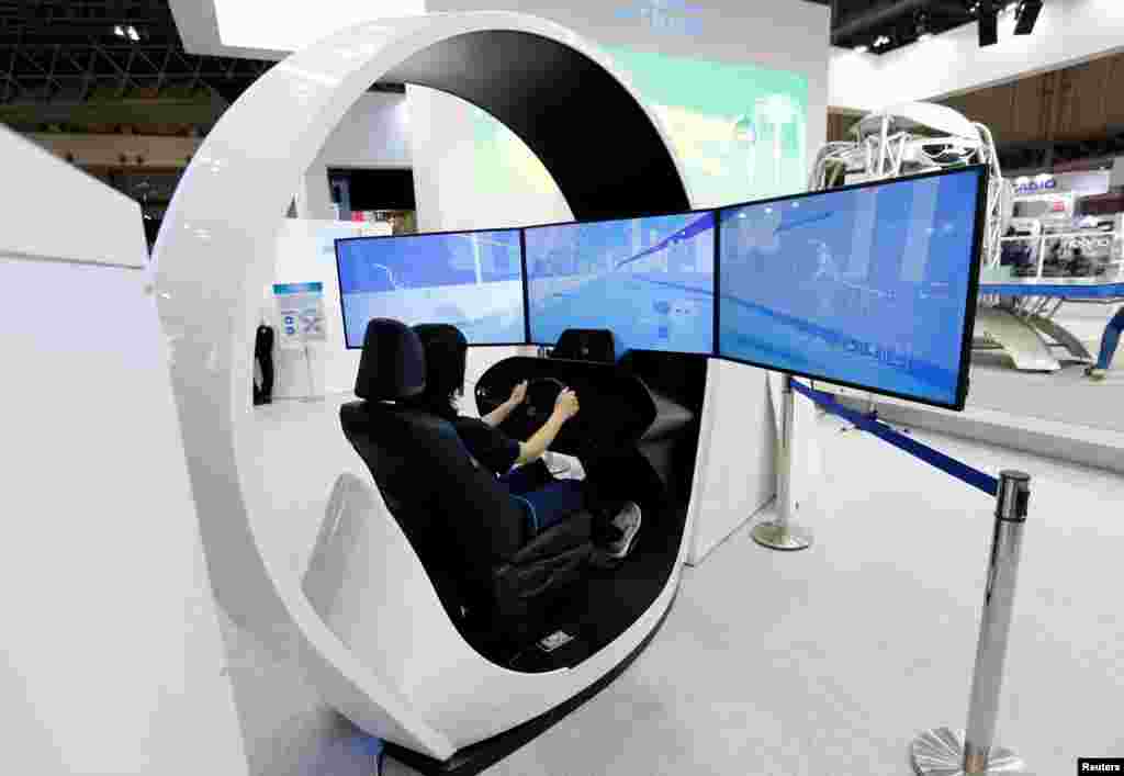A woman demonstrates Omron Corp's 'Onboard Driving Monitoring Sensor', which senses the driver's alertness at CEATEC (Combined Exhibition of Advanced Technologies) JAPAN 2017 at the Makuhari Messe in Chiba, Japan, October 2, 2017.