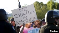 namoyishchilar qo'lidagi plakatda "Amerikada o'rin y'oq" deb yozilgan. Phoenix, Arizona, 2015-yil may