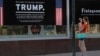 A woman takes a picture of a poster welcoming U.S. President Donald Trump and Russian President Vladimir Putin at a store in downtown Helsinki, July 14, 2018. Trump and Putin will meet Monday at Finnish presidential palace in Helsinki.