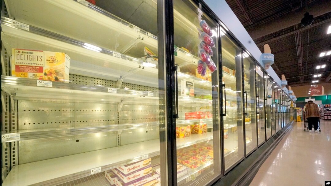 A shopper walks past partially empty frozen food coolers at a grocery in Cranberry Township, Pennsylvania, on Jan. 11, 2022. 