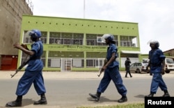 FILE - Riot policemen are seen walking outside the Radio Publique Africaine broadcasting studio in Burundi's capital, Bujumbura, Apr. 26, 2015.