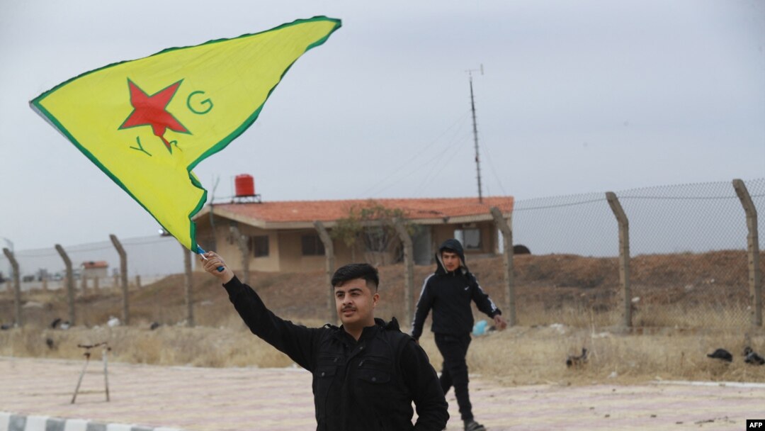 FILE - A Syrian Kurd waves the flag of YPG (People's Protection Units) near Qamishli's airport in northeastern Syria on December 8, 2024, following the fall of the capital Damascus to anti-government fighters.