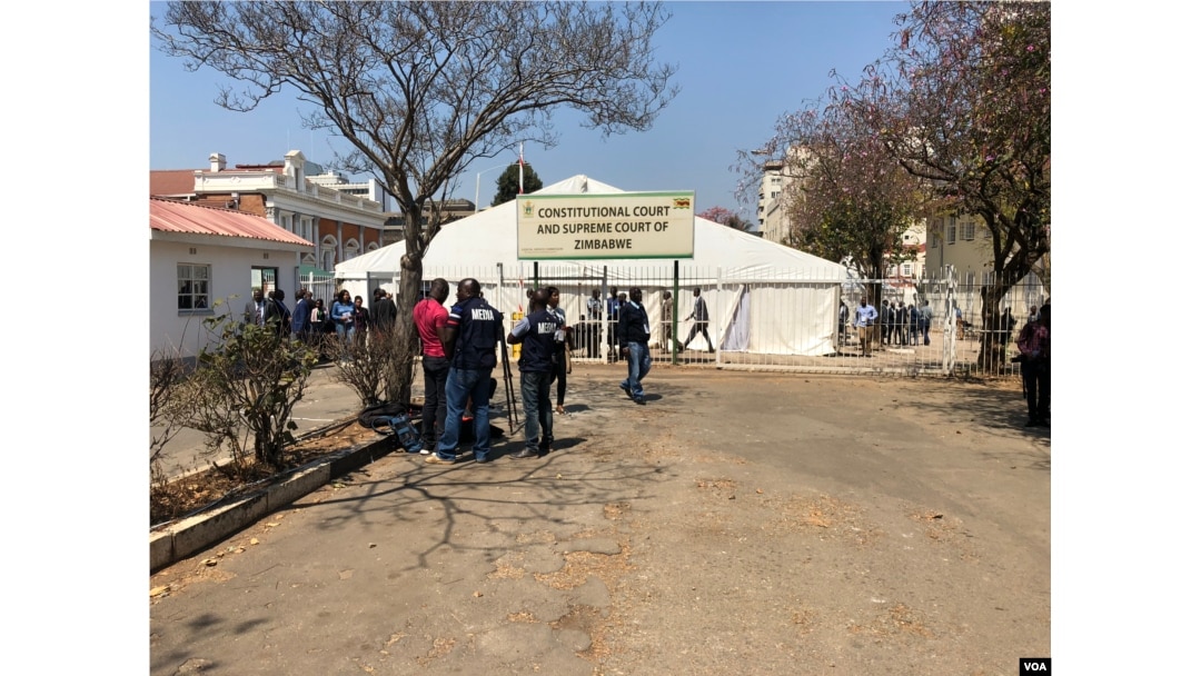 Reporters wait outside Zimbabwe's Constitutional Court in Harare, Aug. 22, 2018, where a presidential election challenge filed by the country's main opposition group was being heard. (C. Mavhunga/VOA)
