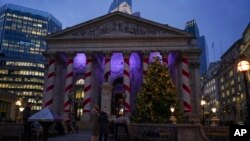 People walk past a Christmas tree outside the Stock Exchange in London, Dec. 4, 2024.