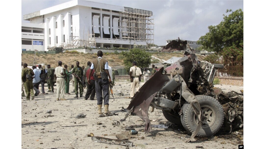 FILE - Somali soldiers stand near the twisted car-bomb that exploded near Somali parliament’s headquarters, in Mogadishu, Somalia, November 7, 2012.