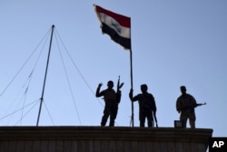 FILE - Iraqi soldiers plant the national flag over a government building in Ramadi as security forces advance their position in northern Ramadi, 115 kilometers (70 miles) west of Baghdad, Iraq, Dec. 21, 2015.