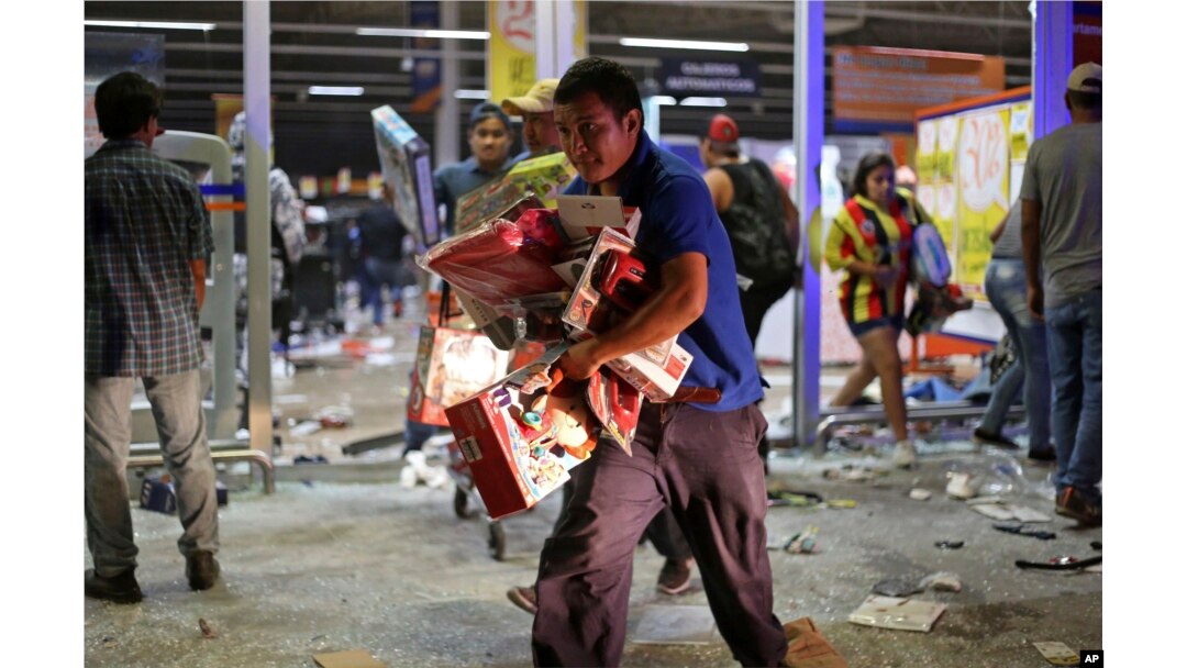 A man runs with toys as a store is ransacked by a crowd in the port of Veracruz, Mexico, Jan. 4, 2017.