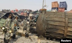 戴着防毒面具的防化兵在天津爆炸现场检查一个大罐子（2015年8月16日）