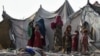 FILE - Children of Afghan refugees play outside tents in the Afghan Basti area on the outskirts of Lahore, Pakistan, June 19, 2021.