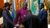 FILE - South Sudan's rebel leader Riek Machar (R) and South Sudan's President Salva Kiir (L) hold a priest's hands before signing an earlier peace agreement in Addis Ababa, Ethiopia, May 9, 2014.
