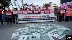 FILE - Fake bank notes showing images of U.S. President Donald Trump are displayed as protesters rally to oppose the U.S. demand for raising costs for stationing U.S. troops in South Korea, near the U.S. Embassy in Seoul, Oct. 22, 2019. 