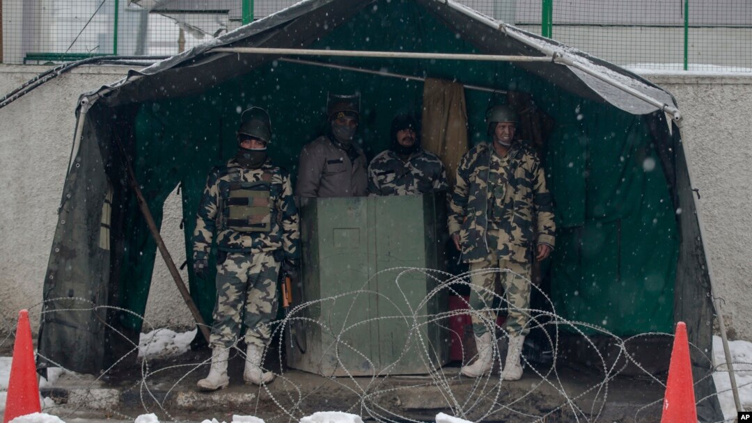 Indian paramilitary soldiers take shelter from snow as they stand guard in Srinagar, Indian controlled Kashmir, Jan. 25, 2017. Four members of a family and an Indian soldier were killed Wednesday when they were buried by two separate avalanches in the Himalayan region of Kashmir, officials said. 