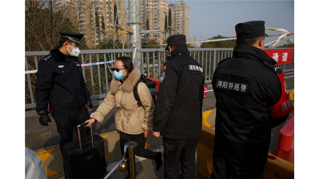 A woman who arrived from Hubei province is permitted through a checkpoint at the Jiujiang Yangtze River Bridge into Jiujiang, Jiangxi province, China, as the country is hit by an outbreak of a new coronavirus, Jan. 31, 2020.