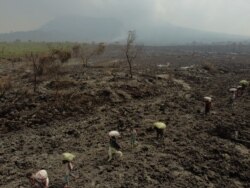 People carry their belongings as they evacuate from recurrent earth tremors as aftershocks after homes were covered with lava deposited by the eruption of Mount Nyiragongo near Goma, in the Democratic Republic of Congo May 25, 2021.