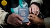 File - Outside a Department of State office, a World War II veteran hold his U.S. passport, June 2, 2014.
