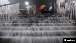 Nước lũ tràn xuống cầu thang ga xe điện ngầm ở Bắc Kinh, ngày 21/7/2012