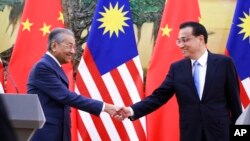 马来西亚总理马哈蒂尔（左）和中国总理李克强在北京人大会堂举行记者会后握手。（2018年8月20日）