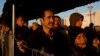 FILE - Syrian refugees stand in a queue to receive food distributed by a nongovernmental organization at a refugee camp at the Greek-Macedonian border near the village of Idomeni, Feb. 25, 2016.