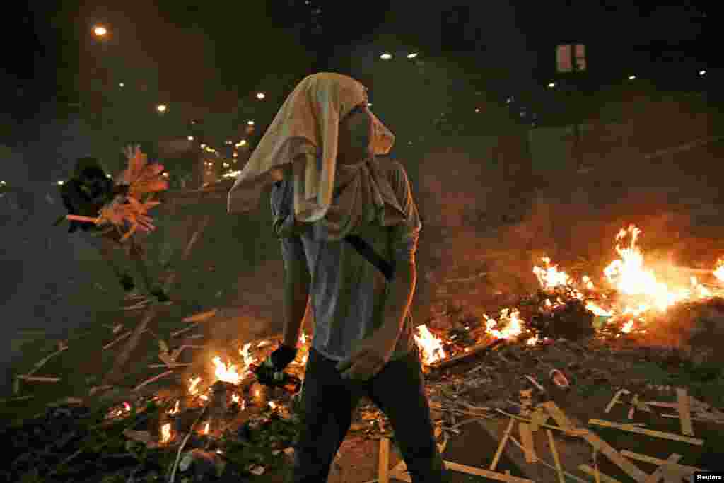 Apoiantes da oposição caminham por entre a barricada em chamas na Praça de Altamira, em Caracas, Fev. 20, 2014.