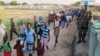 In this handout image from the United Nations Mission in South Sudan taken Dec. 17, 2013 a United Nations soldier stands guard as civilians arrive at UNMISS compound adjacent to the Juba International Airport to take refuge. 