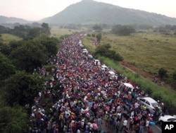 FILE - Members of a U.S.-bound migrant caravan stand on a road outside the town of Arriaga, Oct. 27, 2018.