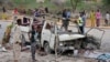 A Somali soldier, left, stands by the wreckage of a minibus that was destroyed in a suicide car bomb attack near the defense ministry compound in Mogadishu, Somalia, April 9, 2017.