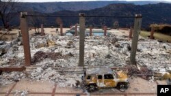 FILE - A vehicle rests in front of a home leveled by the Camp Fire in Paradise, Calif., Dec. 3, 2018. 