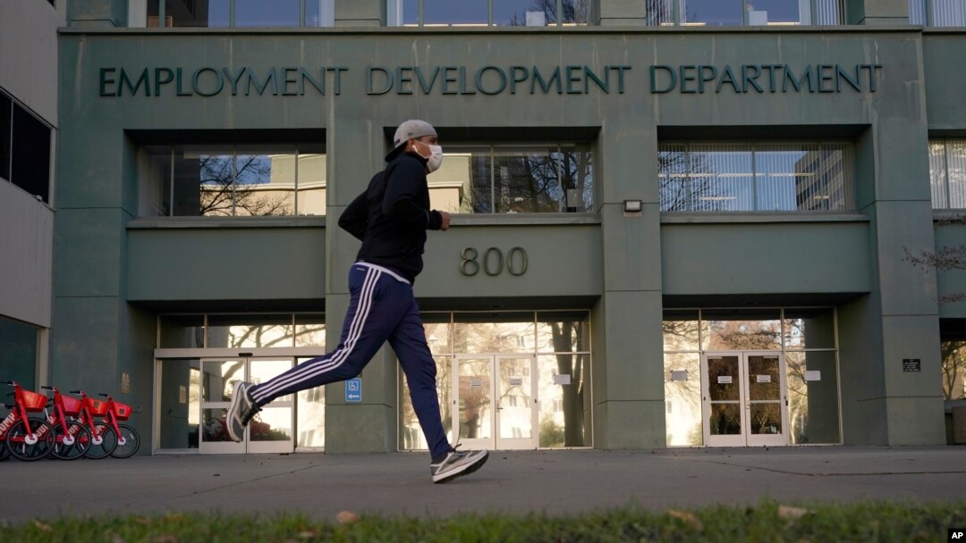 FILE — In his Dec. 18, 2020 file photo a runner passes the office of the California Employment Development Department in Sacramento, Calif. 