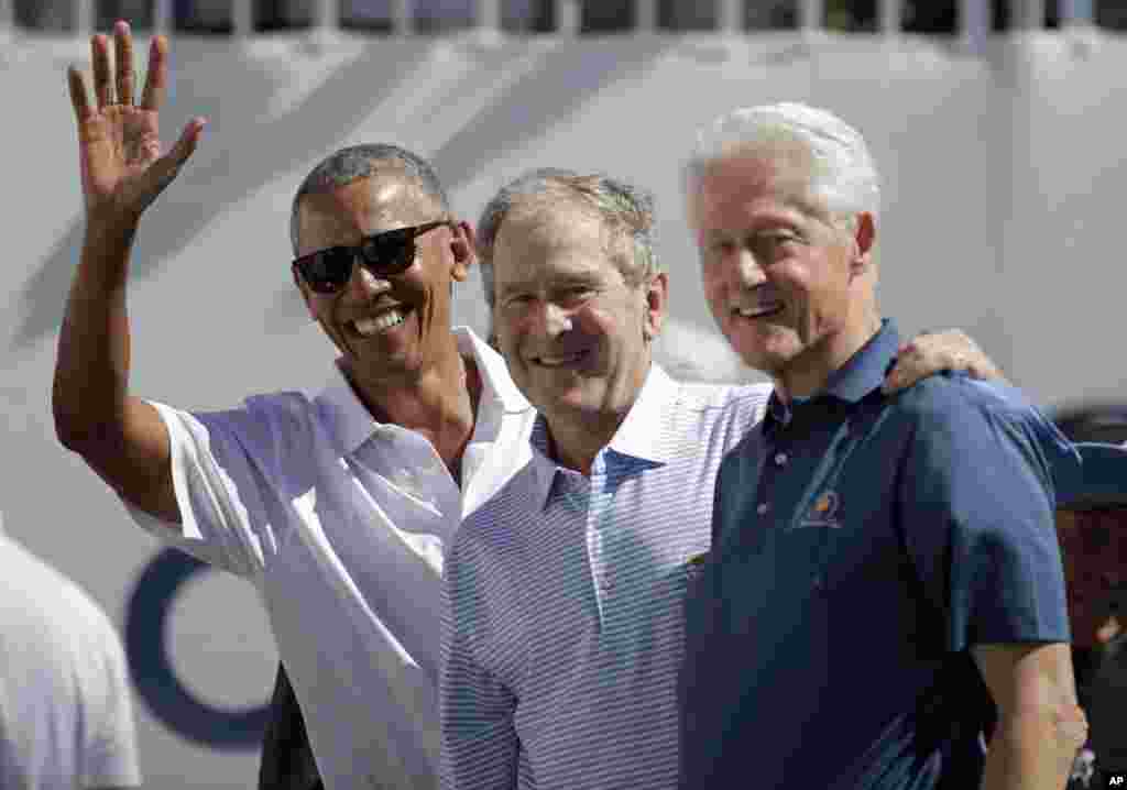 Former U.S. Presidents, from left, Barack Obama, George Bush and Bill Clinton greet spectators on the first tee before the first round of the Presidents Cup at Liberty National Golf Club in Jersey City, New Jersey.