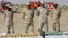 FILE - Iranian police officers stand behind narcotics that were seized at the Milak border in southeastern Iran, Oct. 10, 2012.