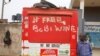 A man leans on a closed kiosk with graffiti calling to free Ugandan opposition presidential candidate Bobi Wine, in Kampala, Uganda, Jan. 17, 2021. 