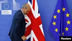 FILE - A worker arranges flags at the EU headquarters as Britain and the EU launch Brexit talks in Brussels, June 19, 2017. 