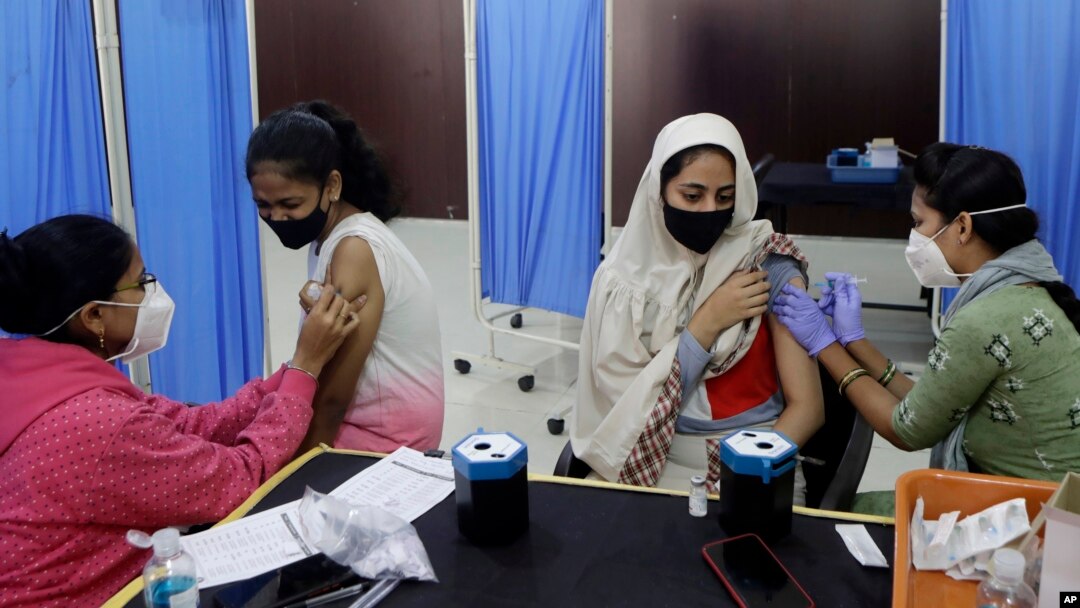 Health workers administer COVID-19 vaccine to women at a vaccination center in Mumbai, India, Friday, Jan. 7, 2022. 