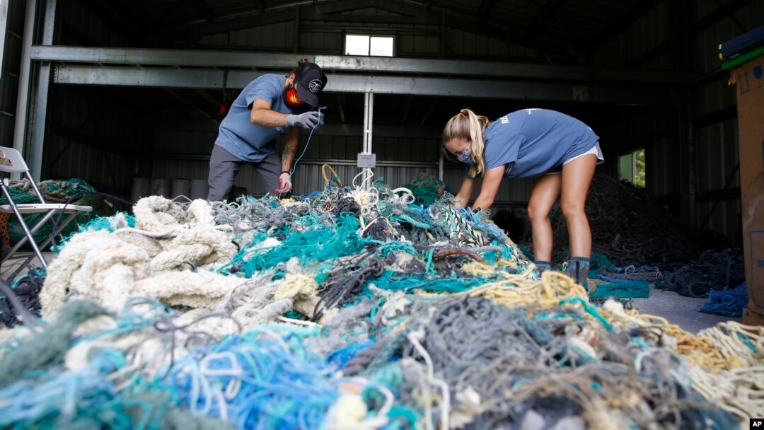 Hawaii Pacific University graduate student Drew McWhirter, left, and Raquel Corniuk, a research technician at the university's Center for Marine Debris Research, pull apart a massive entanglement of ghost nets on Wednesday, May 12, 2021 in Kaneohe, Hawaii. (AP Photo/Caleb Jones)