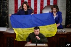 Віце-президентка Камала Гарріс і екс-спікерка Палати представників Ненсі Пелосі із українським прапором із автографами боронців Бахмута під час звернення Зеленського до Конгресу США 21 грудня 2022 року. (AP Photo/Jacquelyn Martin, файл)