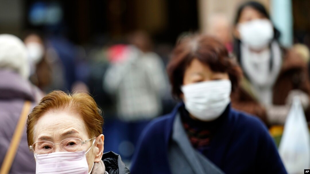 Pedestrians wear protective masks as they walk through a shopping district in Tokyo Thursday, Jan. 16, 2020. Japan's government said Thursday a man treated for pneumonia after returning from China has tested positive for the new coronavirus…