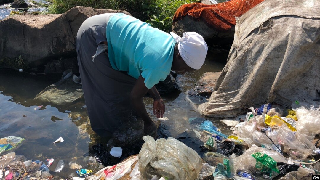 Owesifazana ugezisa izigqoko emfuleni uMukuvisi eHarare. (C. Mavhunga/VOA)