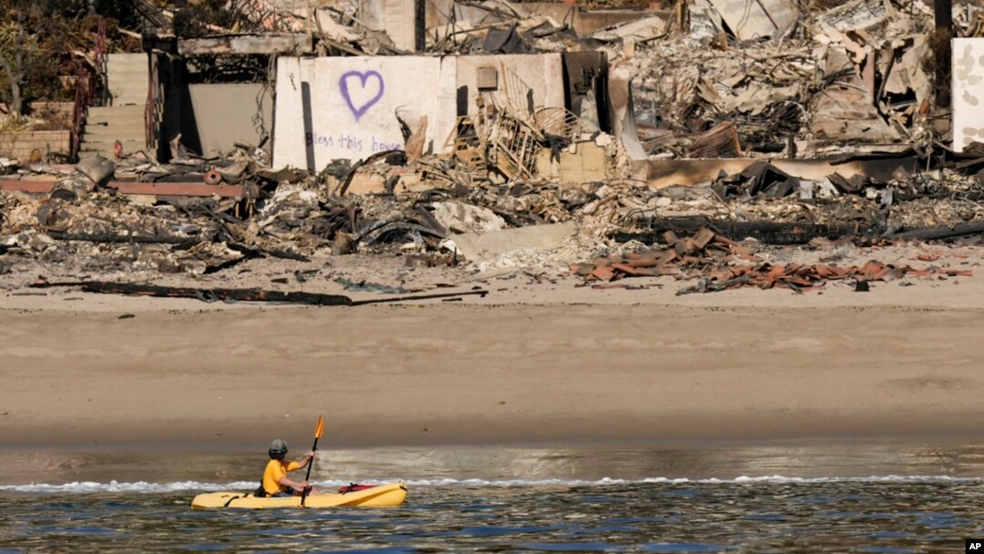 A kayaker goes past a row of homes damaged by the Palisades Fire, Jan. 15, 2025, in Malibu, Calif. 