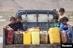 FILE - Children ride on the back of a truck loaded with water jerrycans at a camp for internally displaced people in the Dhanah area of the central province of Marib, Yemen, April 30, 2016.