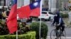 FILE - This photo taken on Dec. 22, 2023, shows a cyclist next to two Taiwanese national flags in Taipei.