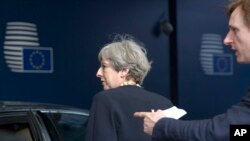 FILE - British Prime Minister Theresa May, left, is guided to her car as she leaves an EU summit at the Europa building in Brussels, Belgium, June 22, 2017.
