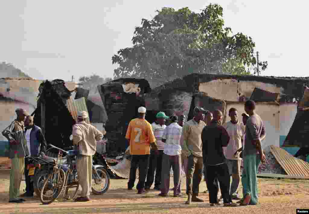 Mahalliy aholi vakillari Mpeketonida jangarilar vayron qilgan binolarni ko'zdan kechirmoqda, 16-iyun, 2014-yil.
