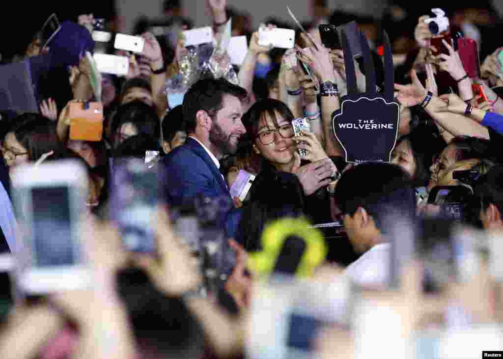 Actor Hugh Jackman takes photographs with a fan during a red carpet event to promote his new movie &quot;The Wolverine&quot; at the Coex Convention and Exhibition Center in Seoul, South Korea.