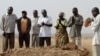 A family gathers around the grave, where three murdered family members were buried together, in Jos in Nigeria's Plateau state, December 28, 2011. Armed Fulani herdsmen shot dead three members of a family in an attack in Nigeria's ethnically and religious