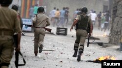 Indian police chase protesters during a strike called by separatists against the recent killings in Kashmir, Sept. 21, 2013.