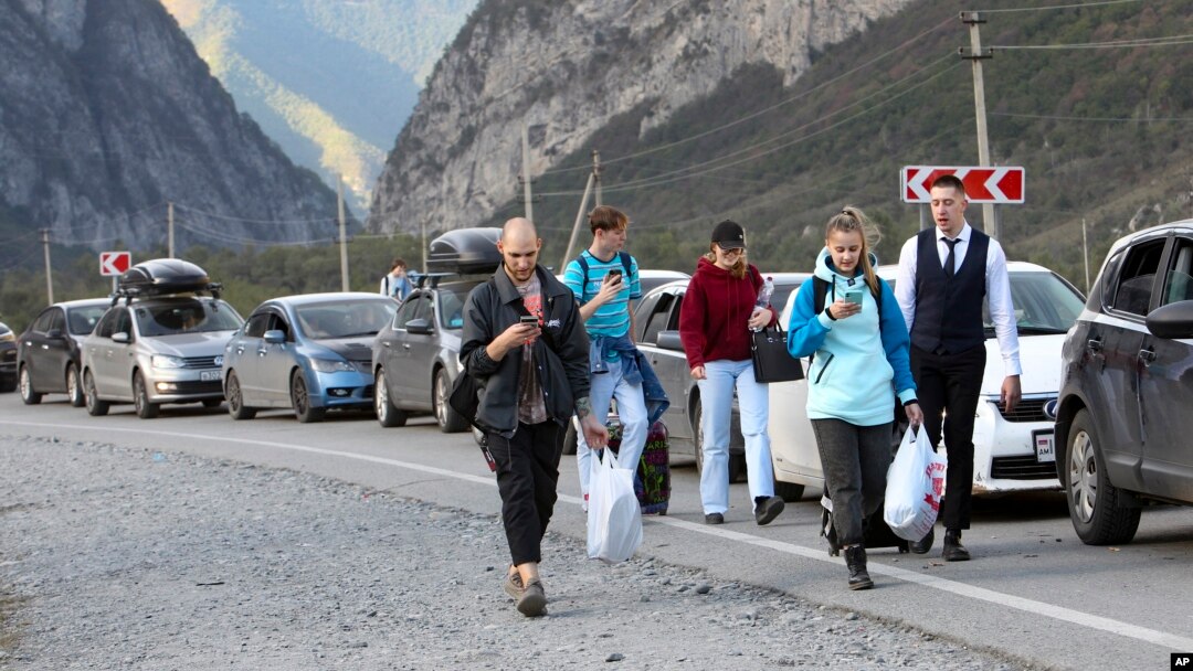 People walk toward the border crossing at Verkhny Lars between Georgia and Russia Wednesday, Sept. 28, 2022. (AP Photo)