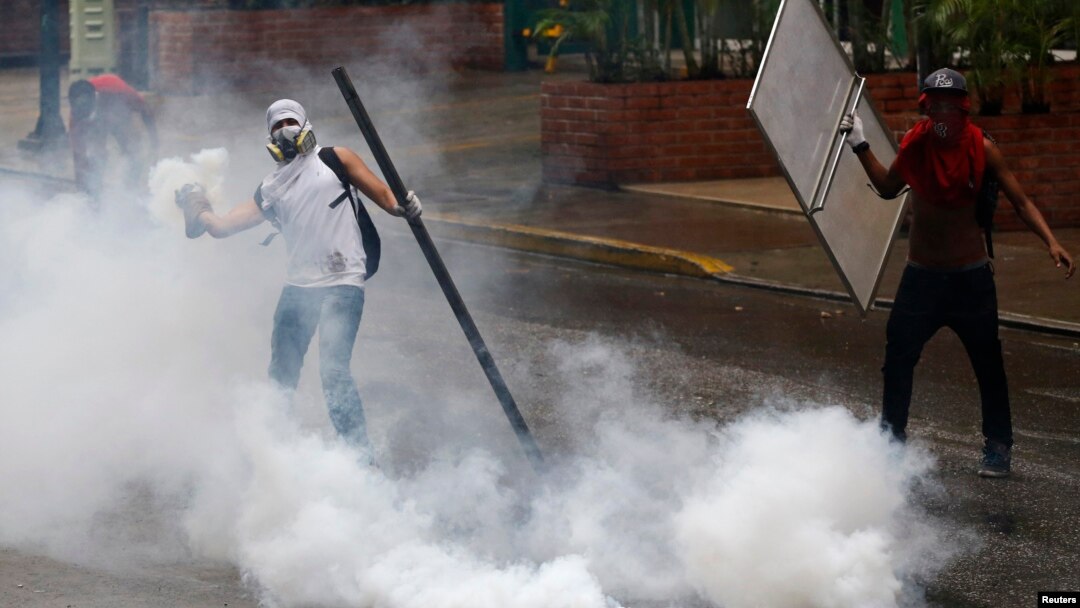 An anti-government protester throws a tear gas canister back at police during a protest against President Nicolas Maduro's government in Caracas, May 8, 2014.